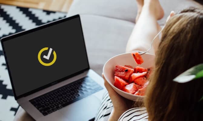 Woman eating berries beside open Laptop